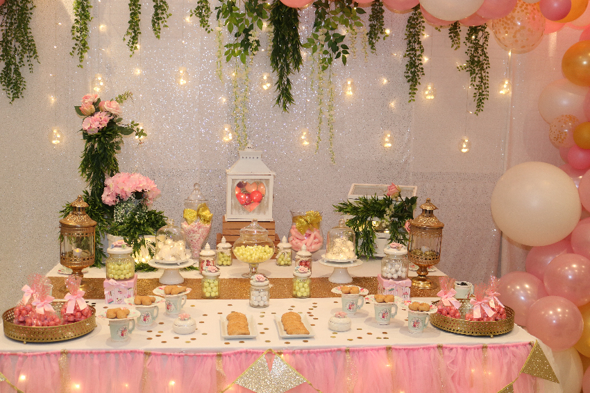 Una mesa dulce y una estructura de globos rosa y dorado para la comunión de Teresa